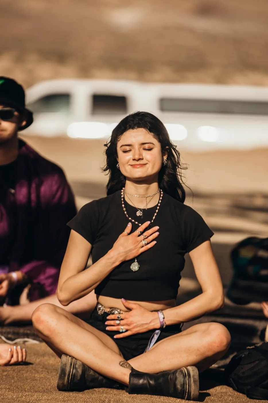 A woman sitting cross-legged with eyes closed and a hand on her heart